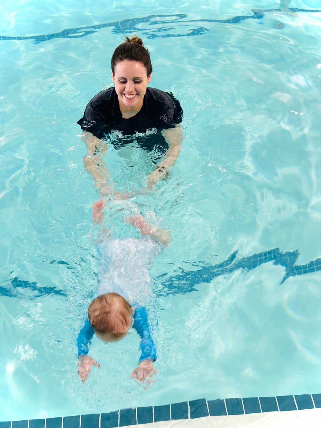 The instructor guiding a baby to glide through the water