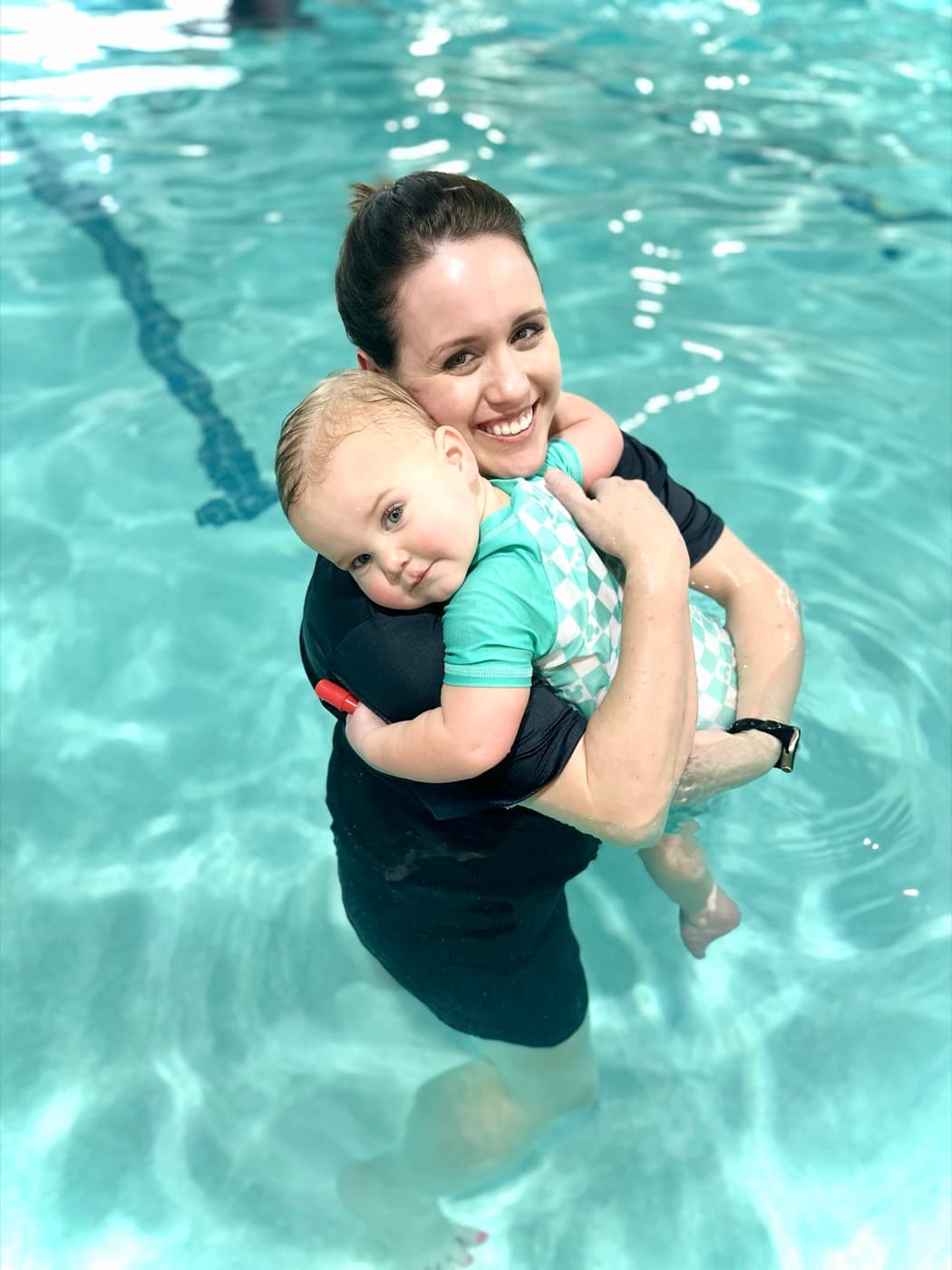 Katrina hugging a happy toddler in the pool