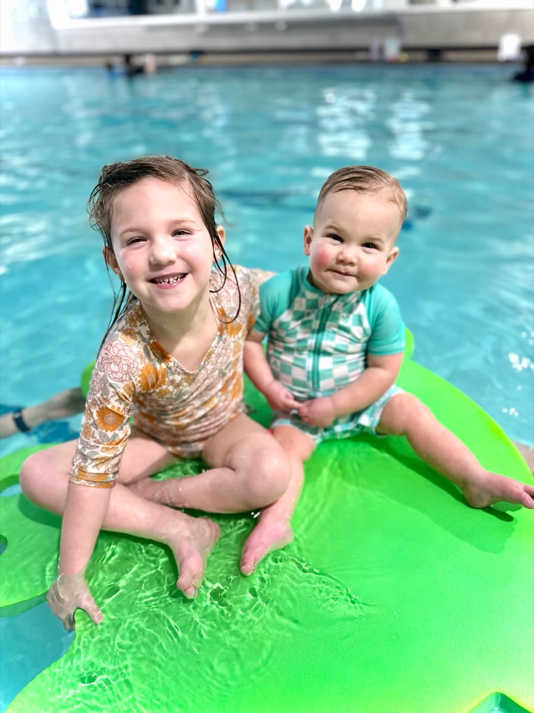 Two happy kids sitting on a pool float together